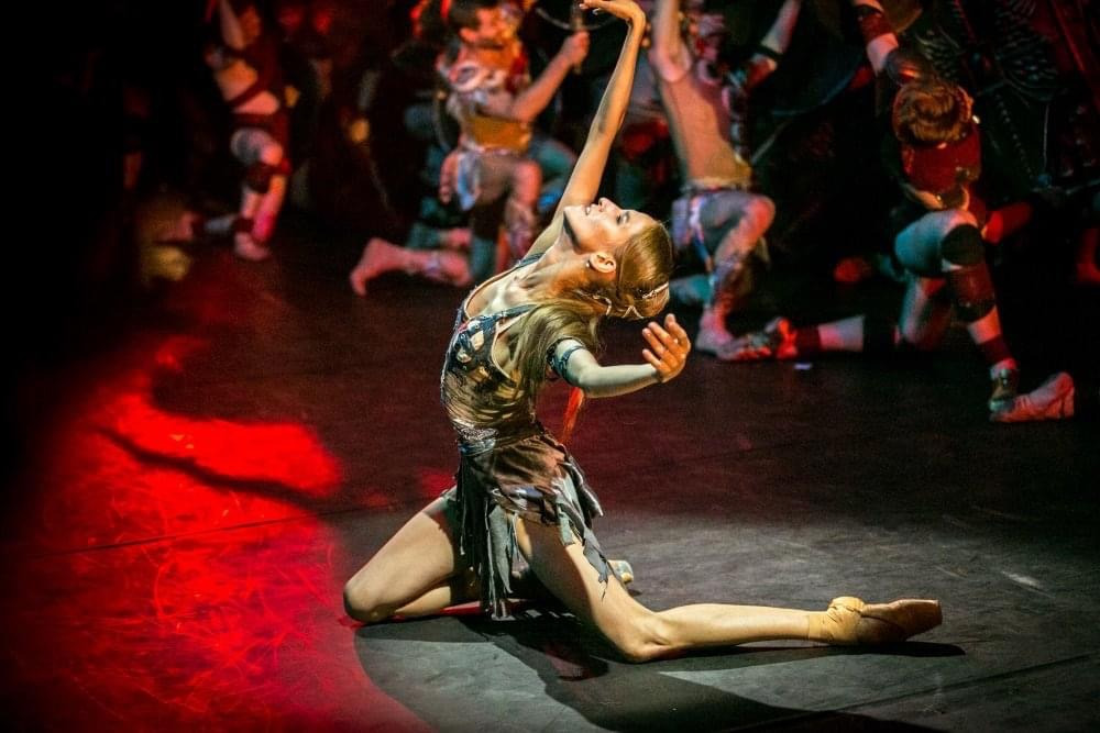 A dancer reaches upwards during a contemporary stage performance